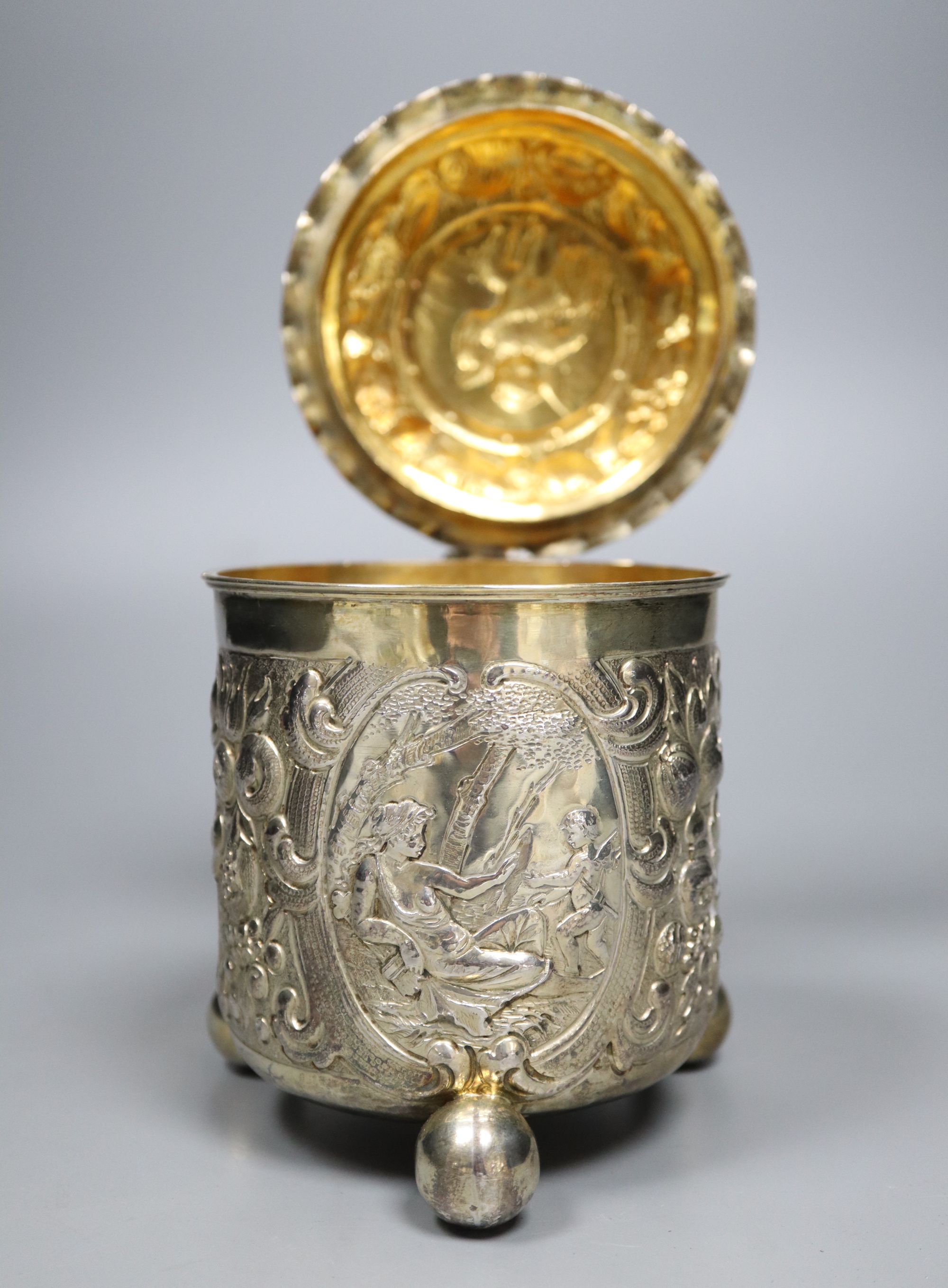 A late 19th century German? silver Scandinavian style embossed lidded tankard, on three ball feet,